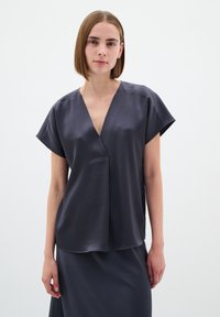Mørkegrå, kortærmet top med V-udskæring og en afslappet pasform. Lavet af et glat, struktureret stof. Enkel, minimalistisk design.