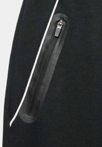 Schwarze Sporthose mit einer Reißverschlusstasche und glattem Rand, einem strukturierten Stoff und einem kontrastierenden weißen Stich an der Naht.