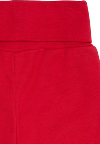 Rote Baumwollleggings mit einem breiten, gerippten Bund und glatter Textur, die eine taillierte Silhouette und keine sichtbaren Nähte oder Muster aufweisen.