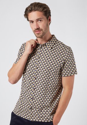 Chemise à manches courtes avec des boutons, présentant un motif géométrique en marine, beige et olive. Fabriquée en tissu léger avec un col classique.
