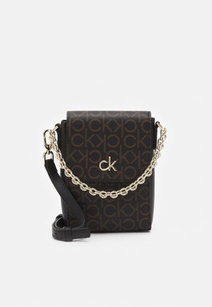 Mała czarna torebka na ramię z brązowym nadrukiem logo Calvin Klein, złotym emblematem "ck" na klapce, złotym łańcuszkiem oraz regulowanym skórzanym paskiem.