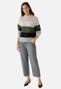 Strickpullover mit horizontalen Streifen in zartem Rosa, Grau, Dunkelgrün und Schwarz, mit einem strukturierten Muster. Getragen mit grauen Jeans und schwarzen Schuhen.
