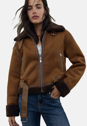 Bruine shearling jas met een bontkraag, ritssluiting aan de voorkant, zijzakken en leren accenten. Heeft een ceintuur in de taille en gestructureerde manchetten.