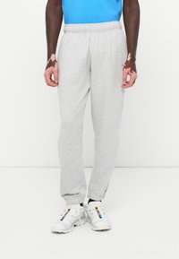 Grå sweatpants med elastisk talje, indsnævrede manchetter og en blød tekstur. Bært med hvide sneakers med farvede accenter.