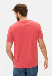 Koralfarvet t-shirt med korte ærmer og rund hals, lavet af blødt bomuldsstof; har en glat overflade og casual pasform.