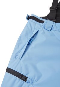 Pantaloni impermeabili de culoare albastru deschis, cu o fermoar lateral, bretele ajustabile și un material robust pentru durabilitate. Detalii negre lângă buzunare.