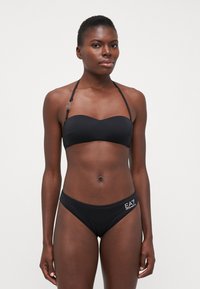 Crni bikini s topom bez naramenica i donjim dijelom s niskim strukom, izrađen od glatkog materijala s logom na strani.