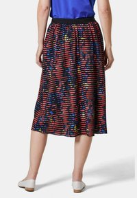 Jupe multicolore jusqu'aux genoux avec un fond noir et des rayures rouges et bleues, taille élastique et tissu léger.