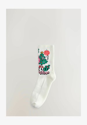 Weißer Socken mit buntem Cartoon-Weihnachtsbaum, rotem Ornament, Stechpalme und dem Text "Vibes" auf einem schlichten hellen Hintergrund.