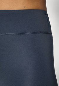 Sötétkék, magas derekú leggings sima, könnyű anyagból; lapos varrásokkal a kényelem érdekében és minimalista dizájnnal.