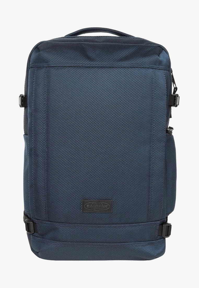 Sac à dos rectangulaire texturé bleu foncé avec une poignée supérieure, des sangles de compression latérales et une étiquette centrale à l'avant avec le logo Eastpak.