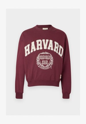 Sweatshirt bordô com "HARVARD" impresso em branco, apresentando um emblema circular com "VERITAS" e acentos decorativos no centro.