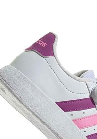 Sneaker in pelle bianca con accenti viola, tre strisce rosa e suola in gomma testurizzata. Presenta un collo imbottito e chiusura con lacci.