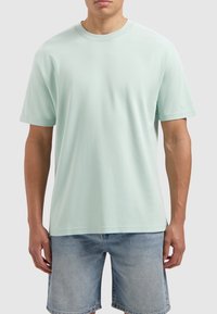 Licht muntgroene korte mouw t-shirt, ronde hals, gemaakt van gladde stof. Gecombineerd met blauwe denim shorts, met een reguliere pasvorm.