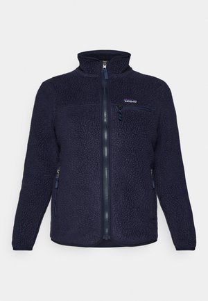 Giacca in pile blu scuro con colletto alto, chiusura con zip, tasche laterali e tasca sul petto. Presenta un tessuto testurizzato e il logo del marchio.