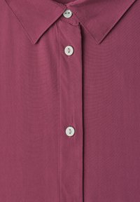 Close-up of a purple collared shirt with three white buttons down the front placket.