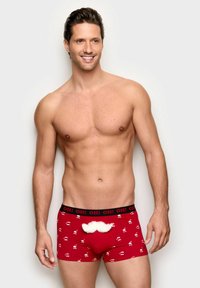 Rote Boxershorts mit einem schwarzen Bund, der den Schriftzug "OH!" und Muster mit weißen Santa-Gesichtern zeigt, einschließlich einem plüschigen weißen Schnurrbart-Detail.