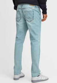 Vaqueros de mezclilla azul claro con un corte recto, que presentan dos bolsillos traseros con acentos de costura y un diseño limpio y minimalista.