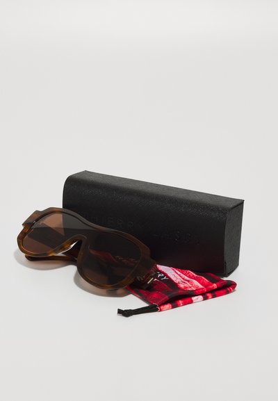 Occhiali da sole in tartaruga marrone con forma oversized, lenti sfumate e robusta montatura in acetato. Custodia nera testurizzata e panno per la pulizia a motivo rosso inclusi.