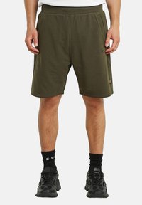 Shorts atletici verde oliva con vita elastica, tasche laterali e un marchio discreto. Realizzati in un morbido tessuto misto cotone.