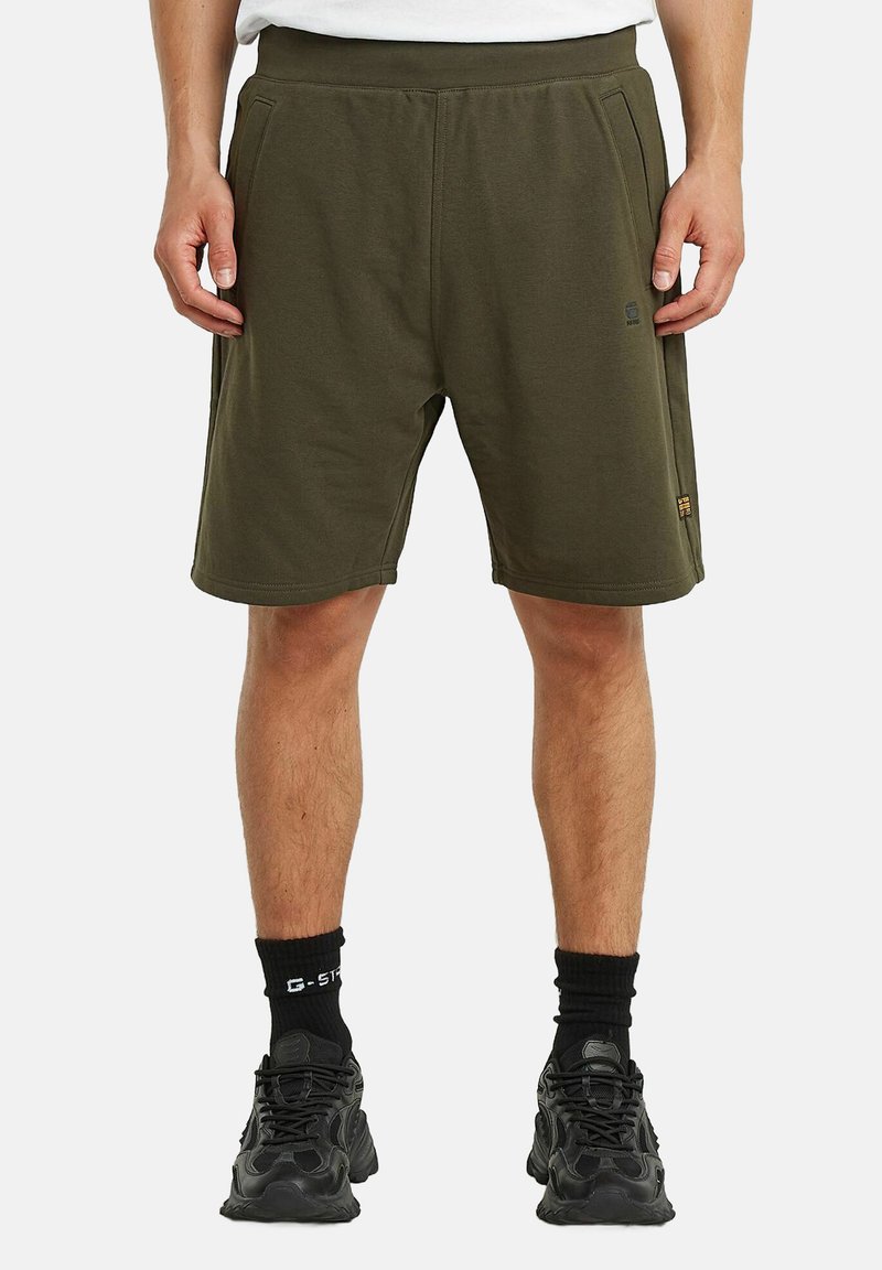 Shorts atletici verde oliva con vita elastica, tasche laterali e un marchio discreto. Realizzati in un morbido tessuto misto cotone.