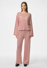 Ensemble de détente en tricot à rayures rouges et blanches, comprenant un haut ample à manches longues et un pantalon large, fabriqué en tissu doux et texturé.