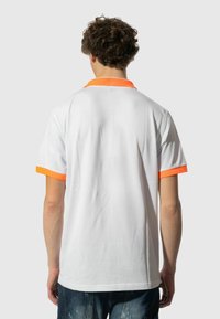 Polo a maniche corte di colore bianco con colletto arancione. Tessuto morbido, vestibilità standard e senza loghi o modelli visibili.
