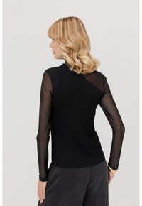Czarny top z długim rękawem, z solidnym korpusem i przezroczystymi rękawami z siateczki, o dopasowanym fasonie i minimalnym dekolcie.