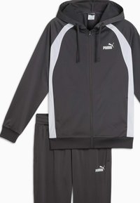 Chándal PUMA en gris oscuro con acentos blancos. Cuenta con una sudadera con cierre y cordones, y una cinturilla elástica en los pantalones. Textura suave.