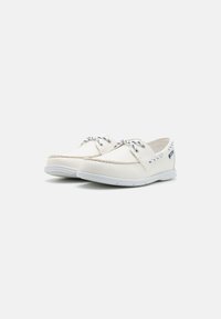 Weiße Segelschuhe aus Canvas mit runder Zehenpartie, dekorativer Naht und marineblauen Schnürdetails. Gummisohle für Grip und Unterstützung.