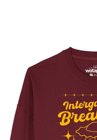Bordeaux sweatshirt met een ronde halslijn en lange mouwen. Voorzien van gele grafische tekst "Intergalactic Breakfast" en een donutillustratie.