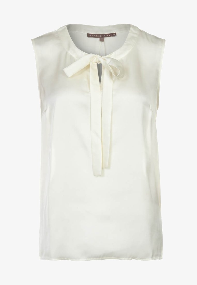 Bezrukává krémová blůza z hladkého materiálu, s kulatým výstřihem a mašlí vpředu. Bez viditelných vzorů nebo akcentů.