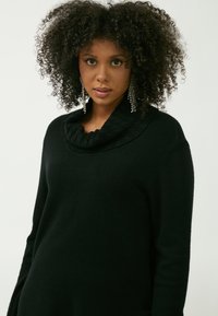 Schwarzer Pullover mit Kapuze aus weichem Strickstoff, mit einem strukturierten Kragen, langen Ärmeln und einer legeren Passform.