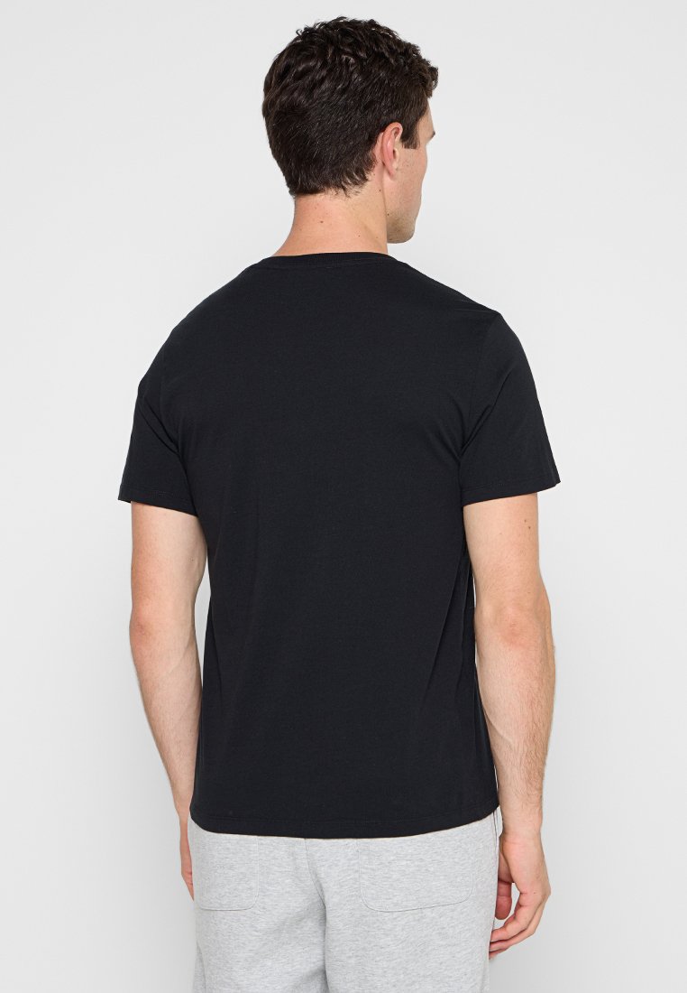 Camiseta de algodón negra con mangas cortas y un escote redondo, con un diseño liso y un ajuste regular, vista desde la parte posterior.