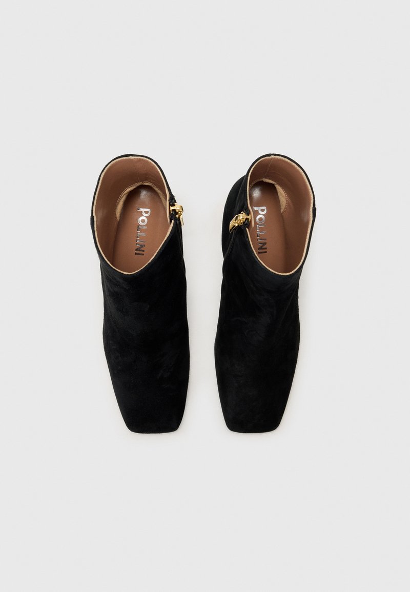 Bottines en daim noir avec des orteils carrés, des zips sur le côté et des accessoires en ton doré. L'intérieur présente une semelle brune avec un logo.