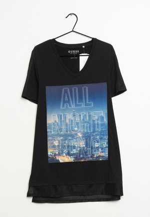 Czarny t-shirt z dekoltem w serek z grafikiem przedstawiającym panoramę miasta oraz napisem "CAŁĄ NOC" wydrukowanym z przodu, wiszący na czarnym wieszaku.