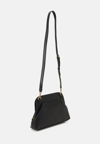 Sac à main en cuir noir avec une forme structurée, doté d'une longue bandoulière amovible et d'accents en métal doré. Texture lisse, design minimaliste.