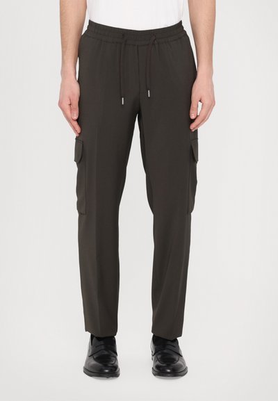 Pantalons cargo en vert olive foncé. Dotés d'une taille élastique avec cordons de serrage et de deux poches latérales ; texture lisse et coupe ajustée.