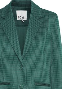 Zeleni karo sako od teksturiranog tkanja, s urezanim reverom, dva gumba i dva prednja džepa. Oznaka glasi "ICHI."