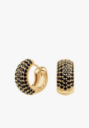 Złote kolczyki w kształcie kółek z teksturowaną powierzchnią ozdobioną czarnymi kamieniami, prezentujące zakrzywiony kształt i błyszczące wykończenie.