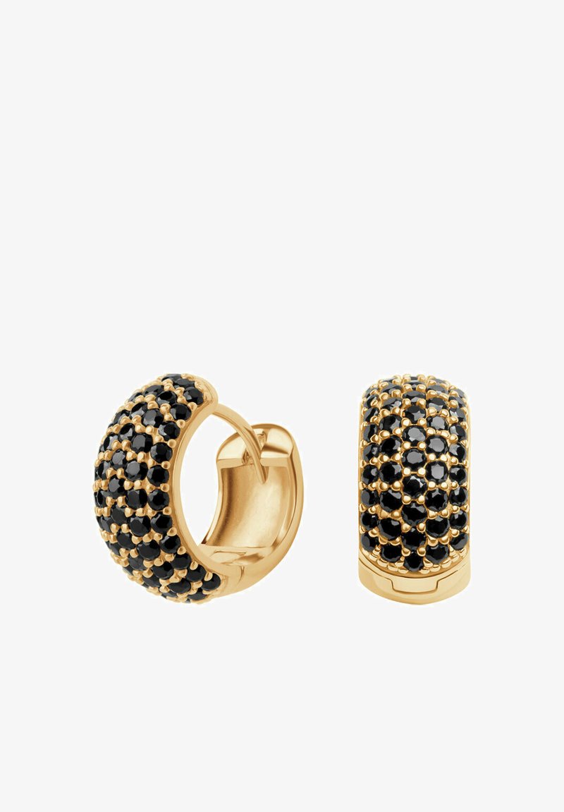 Złote kolczyki w kształcie kółek z teksturowaną powierzchnią ozdobioną czarnymi kamieniami, prezentujące zakrzywiony kształt i błyszczące wykończenie.