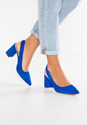 Niebieskie zamszowe buty na obcasie, z odkrytymi piętami, w kształcie szpiczastego nosa i szerokim obcasie. Z tyłu są otwarte, odsłaniając skórę nad kostką.