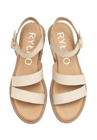 Beżowe skórzane sandały z trzema szerokimi paskami i paskiem na kostkę z tyłu. Posiadają płaską podeszwę i dekoracyjne przeszycia wzdłuż krawędzi.