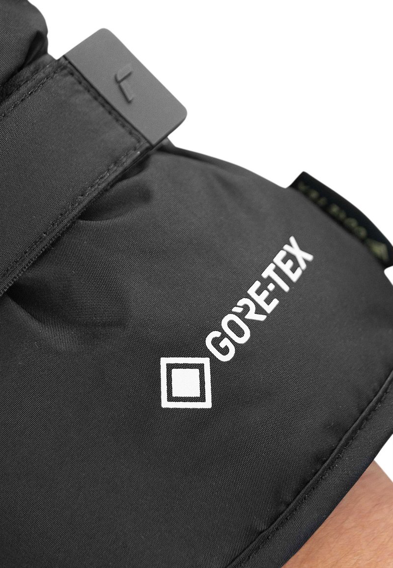 Schwarzer Gore-Tex-Stoff mit glatter Textur. Verfügt über ein quadratisches Logo und einen schwarzen Verschluss. Sichtbares Nähdetail entlang der Naht.