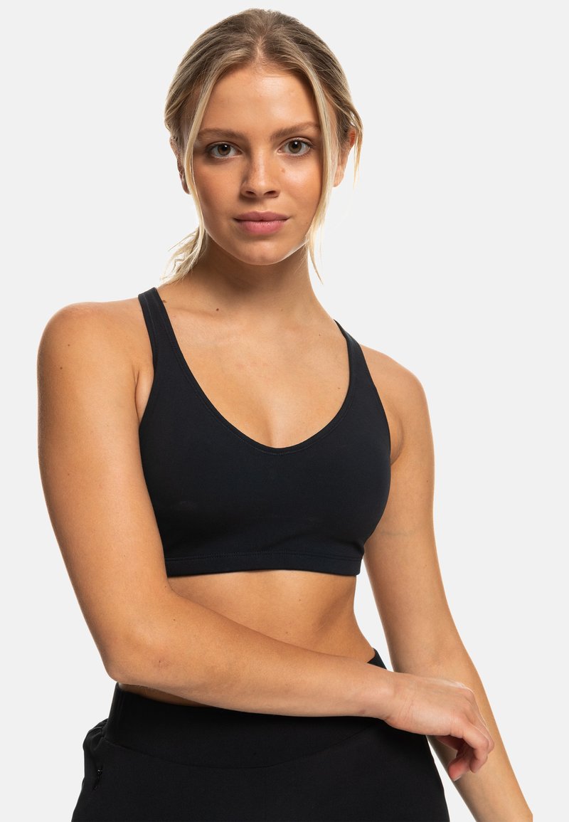 Sostén deportivo negro con diseño de cuello en V y tirantes finos. Tela suave, forma ajustada y sin herrajes o patrones visibles.
