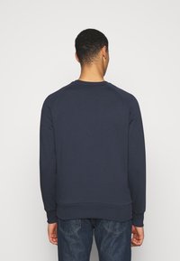Marinblå sweatshirt gjord av mjuk bomullsblandning med långa ärmar, rund halsringning och ribbade muddar och nederkant. Designad med en avslappnad passform.