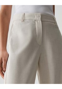 Helle beige Hosen aus strukturiertem Stoff, mit flachem Bund, Seitentaschen und taillierter Passform. Mit Gürtelschlaufen akzentuiert.