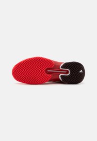 Red and black athletic shoe sole with a herringbone pattern, featuring a smooth surface and contrasting white accents.