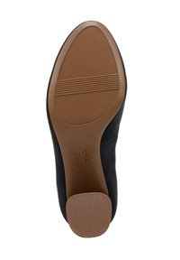 Suola di scarpa in suede nero con una superficie liscia in gomma color beige; presenta scanalature orizzontali per la trazione e un design della punta arrotondato.