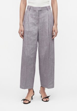 Grå bukser med vide ben og subtile lodrette striber, båret med sorte åbne hæle og en hvid top, vist fra talje til fødder.